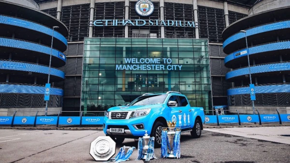 Etihad Stadium do time de futebol Manchester City com caminhonete Nissan plotada na frente