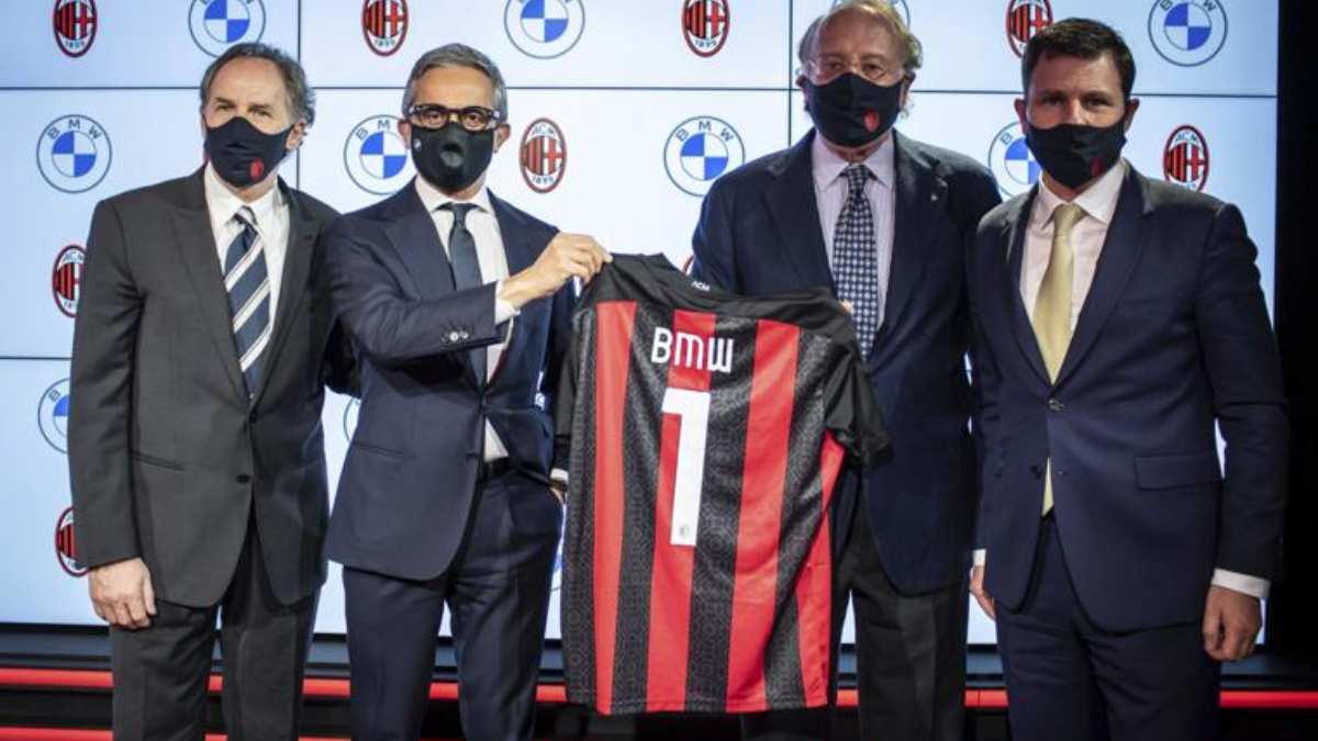 Diretoria do time de futebol AC Milan segurando camisa com nome de uma das marcas alemãs BMW