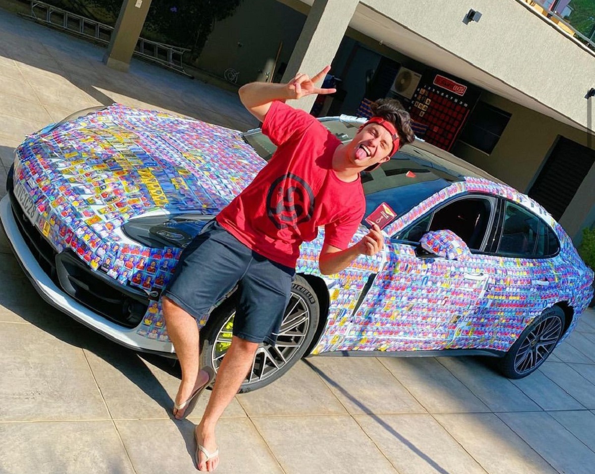 Enaldinho em frente ao seu Porsche Panamera coberta de figurinhas da Copa.