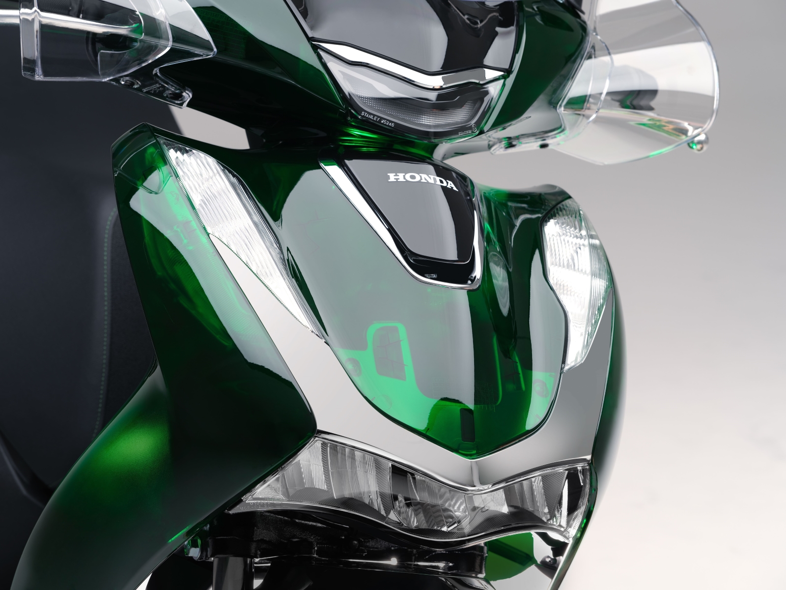 honda sh vetro modelo 2024 verde e preto detalhe da frente farois carenagem transparente estatica no estudio