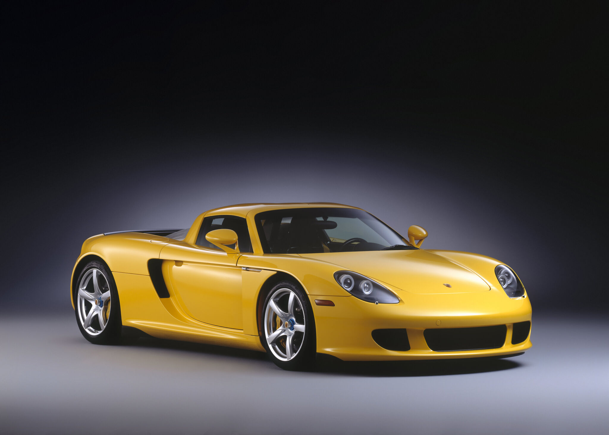 Porsche Carrera GT amarelo estacionado em foto de estúdio