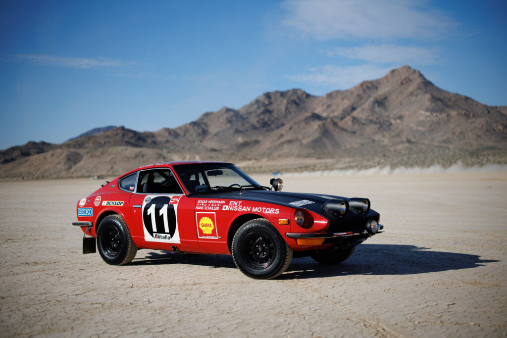 Réplica do Datsun 240Z visto da diagonal frontal em meio à deserto de rally.